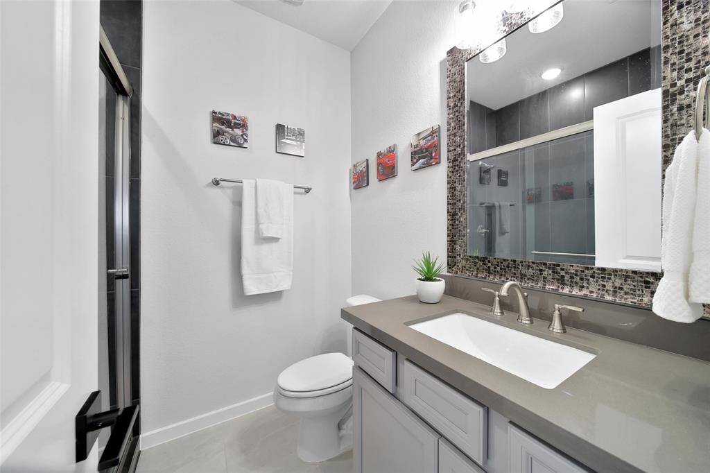 Hallway bath situated between both bedrooms has a walk in shower and handsome quartz countertops on the vanity.