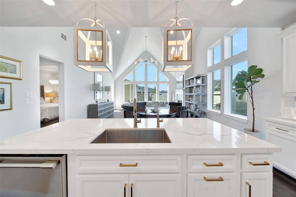 Designer pendant lights illuminate the center island accented by modern brushed gold hardware that can be found on all the kitchen cabinets.
