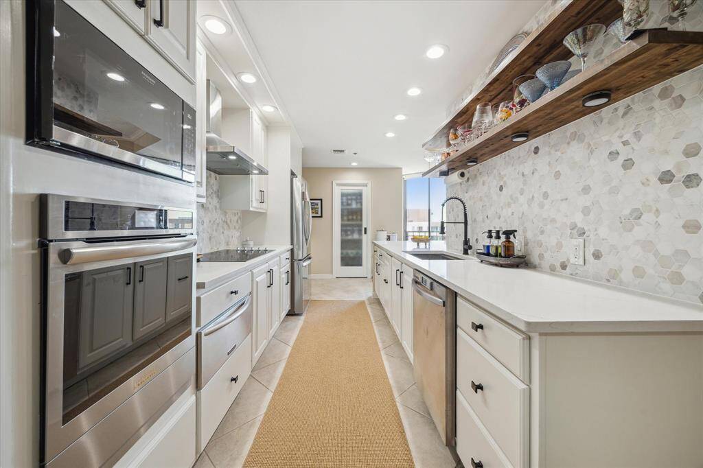 View of the kitchen looking toward the utility room. Owner has added extra wood shelving with undercounter lighitng.