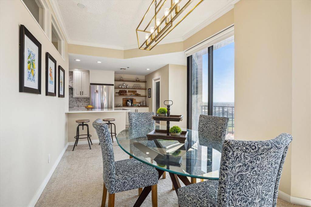 Dining area looking toward kitchen. Enjoy the pretty views from the floor to ceiling windows. Note breakfast bar !!