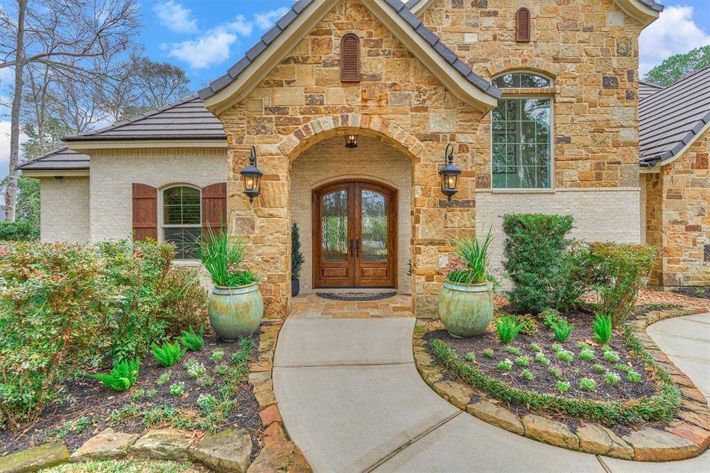 Welcoming front entry with covered porch and double door arched doors.
