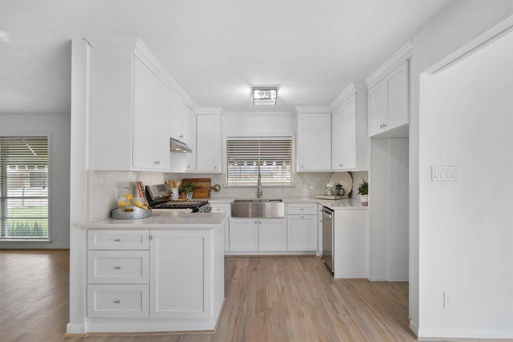 The kitchen has 42" painted Shaker-style cabinets capped with crown moulding accompanied by quartz counter tops (installed in 2024) with quartz back splash and hardwood floors. The counter tops & hardwood floors were installed in 2024.