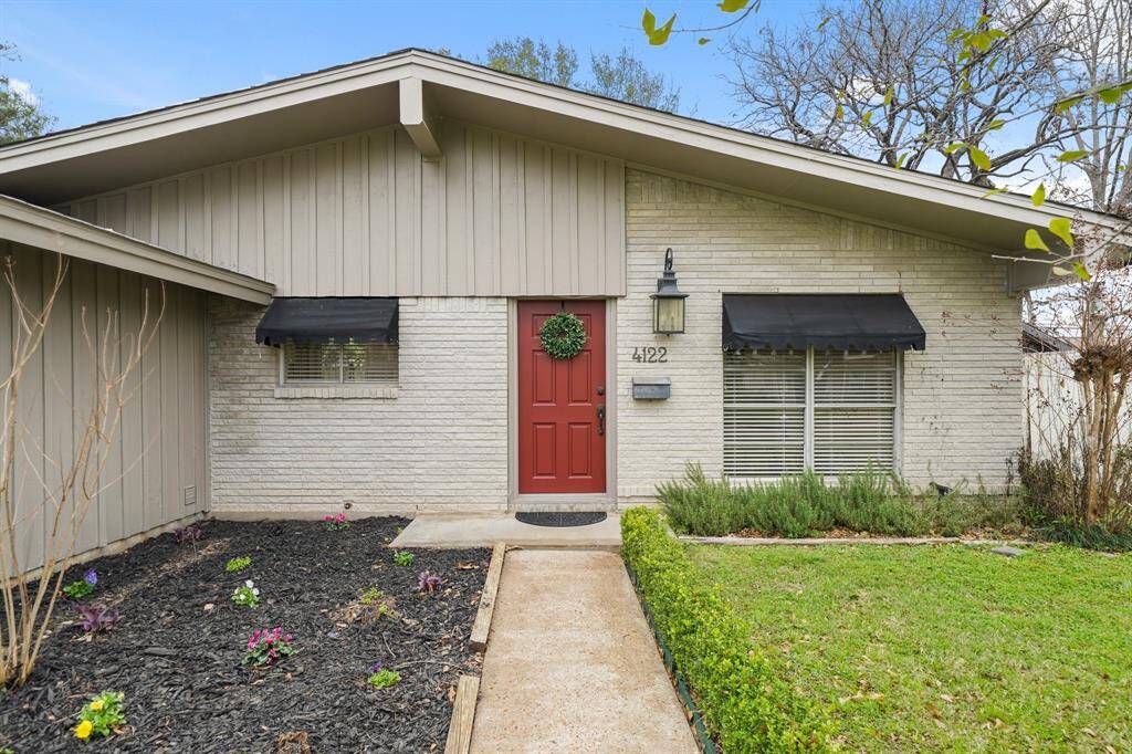 A paved sidewalk leads from the driveway to the front entrance of the home illuminated by coach lantern lighting.
