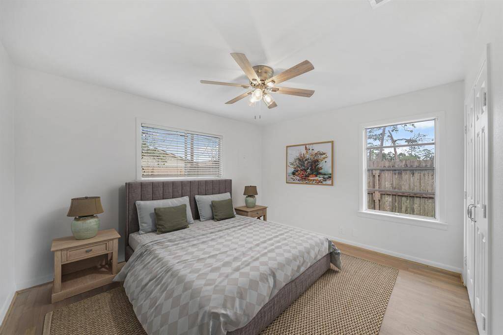 Located on the back of the home, the owner's bedroom features a ceiling fan with lighting, two windows overlooking the backyard & hardwood floors. This photo has been virtually staged.