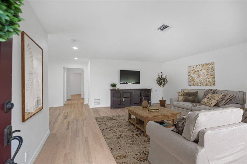 The front entrance of the home opens to the spacious living room with a wall mounted flat screen TV included. This photo has been virtually staged.