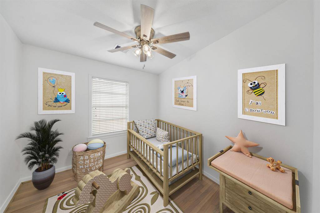 The third bedroom has a ceiling fan with lighting, window with blinds & hardwood flooring. This photo has been virtually staged.