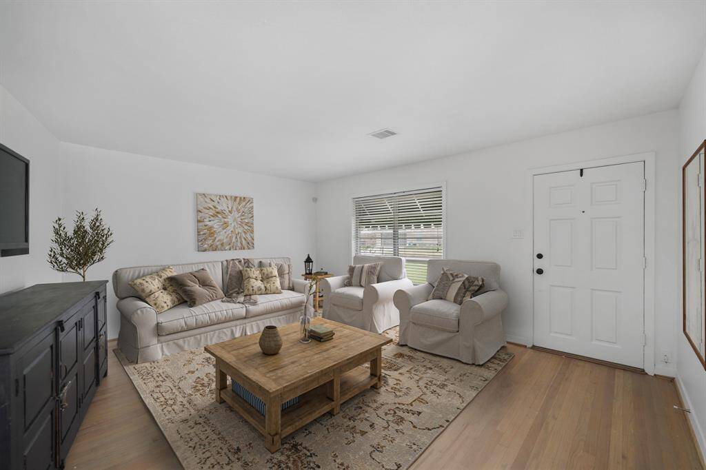 Large windows with blinds overlook the front yard while original hardwood floors grace this beautiful living space. This photo has been virtually staged.
