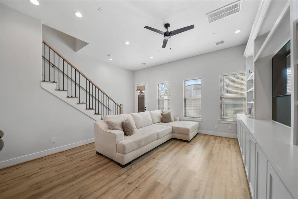 A wrought iron & wood-stained staircase with solid hardwood treads leads to the second level of the home while  the glass door in the background opens to the fenced backyard.