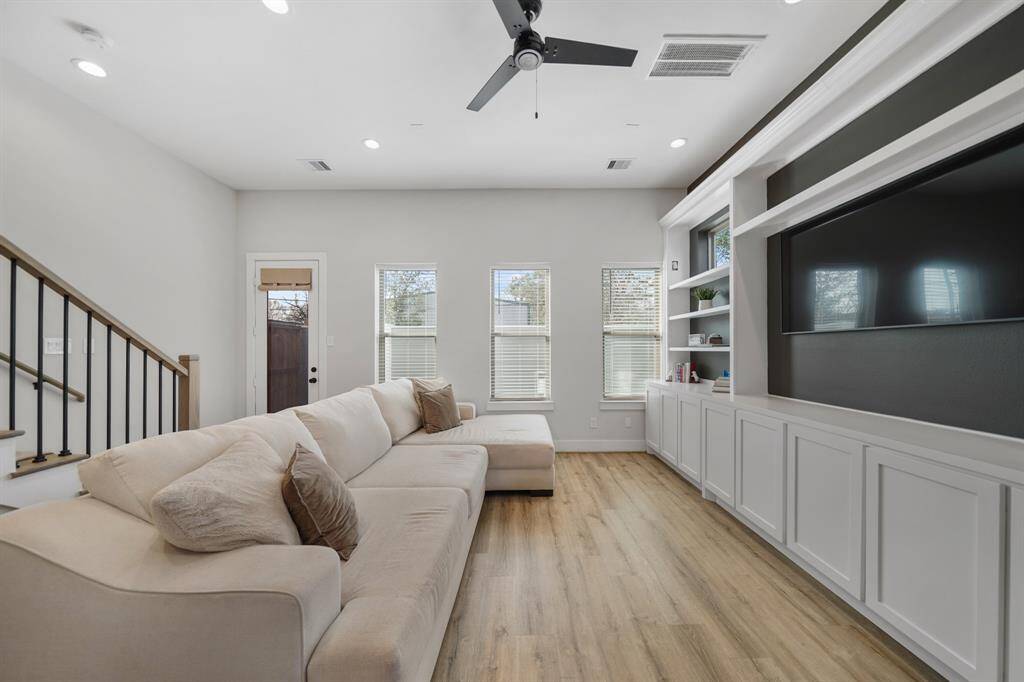 This living space is filled with natural light from the wall of windows with blinds overlooking the backyard.