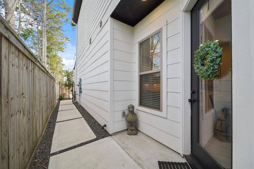 A wrought iron pedestrian gate from the front of the home opens to concrete pavers bordered by crushed granite leading to the covered front porch.