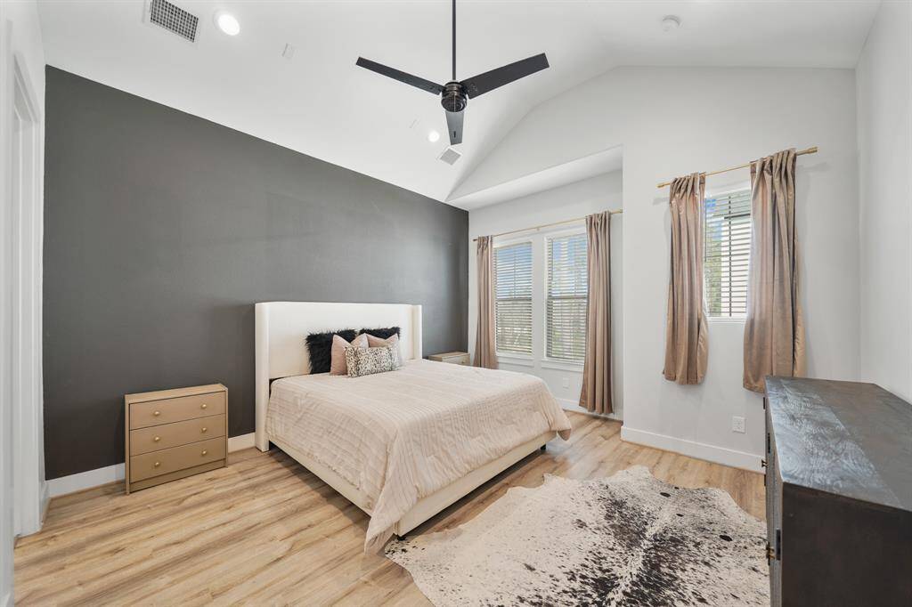 The owner's suite with high ceiling, recessed lights, ceiling fan & pre-wiring for ceiling speakers includes large windows with blinds & drapes overlooking the front of the home and includes luxury vinyl plank hardwood floors.