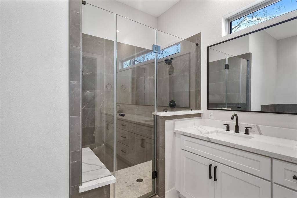 Just next to the dressing area is a tile surrounded & frameless glass enclosed shower with quartz surfaced seating.