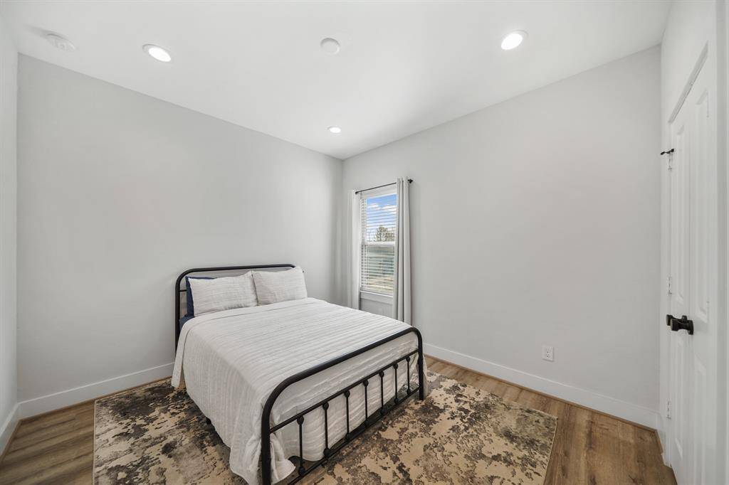 The secondary bedroom has a 9' ceiling with recessed lighting, pre-wiring for a ceiling fan, a window with blinds and drapes overlooking the front of the home with vinyl plank hardwood flooring.