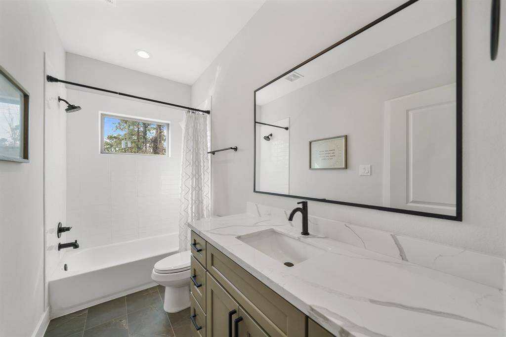 Included is a subway tile surrounded combination tub/shower with black plumbing fixtures.