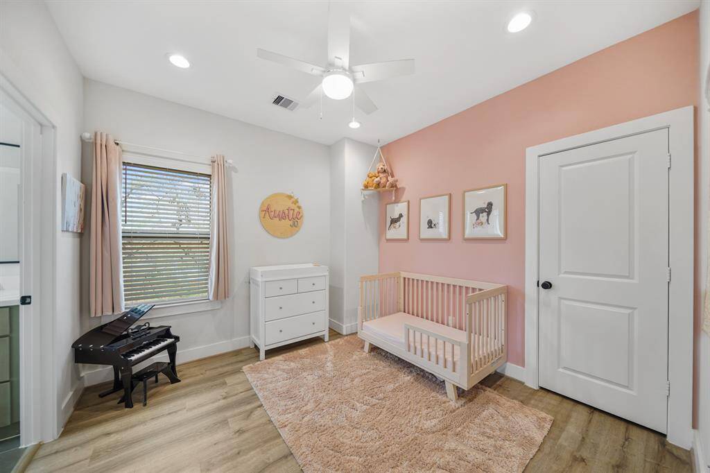 Currently serving as a nursery, the third bedroom has recessed lights, ceiling fan with lighting, a window with blinds and drapes & luxury vinyl plank hardwood floors.