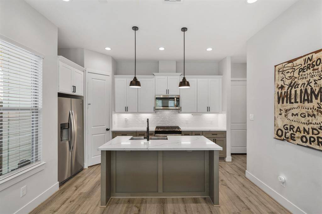Beautifully designed, the gourmet kitchen with island & breakfast bar seating illuminated by pendant lighting includes recessed lighting, 42" painted Shaker-style cabinets capped with crown moulding highlighted by quartz counter tops and a subway tiled back splash with under-cabinet lighting. Notice the accent painted island & lower cabinets in this gorgeous kitchen!