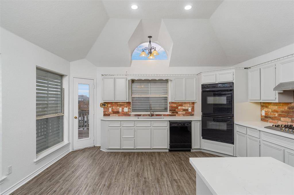 The updated white kitchen is spacious with plenty of room for a large dining table. The white cabinets and quartz are modern looking with the brick backsplash