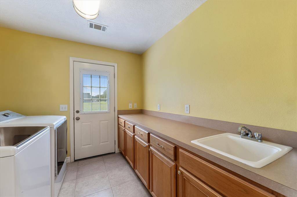 Oversized laundry room with lots of cabinets and sink