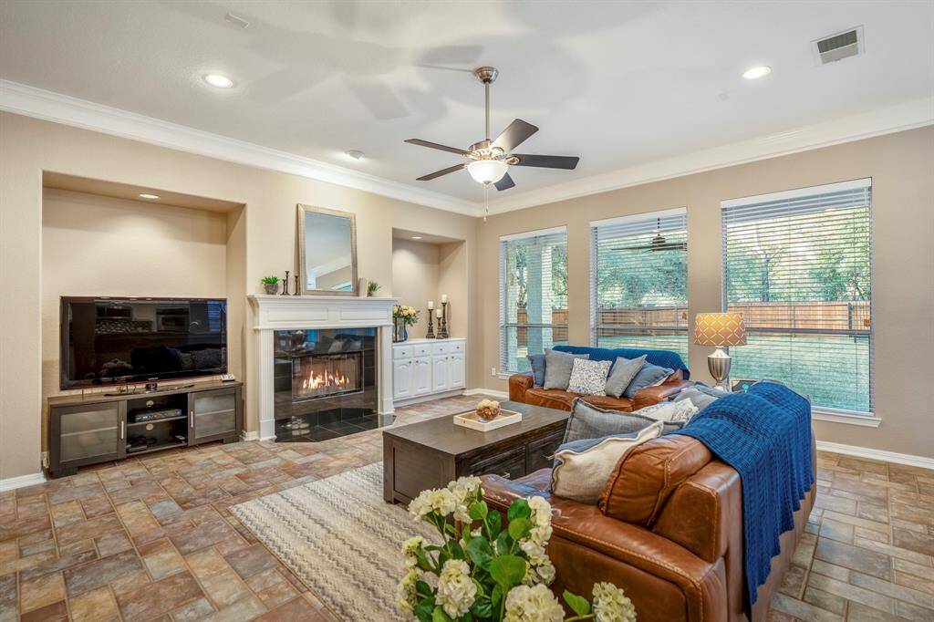 From this vantage point near the fridge, the family room’s centerpiece fireplace takes center stage, with detailed trim around the mantel adding a touch of elegance. The open layout creates a warm, inviting atmosphere, making this a perfect spot for relaxation and entertaining.