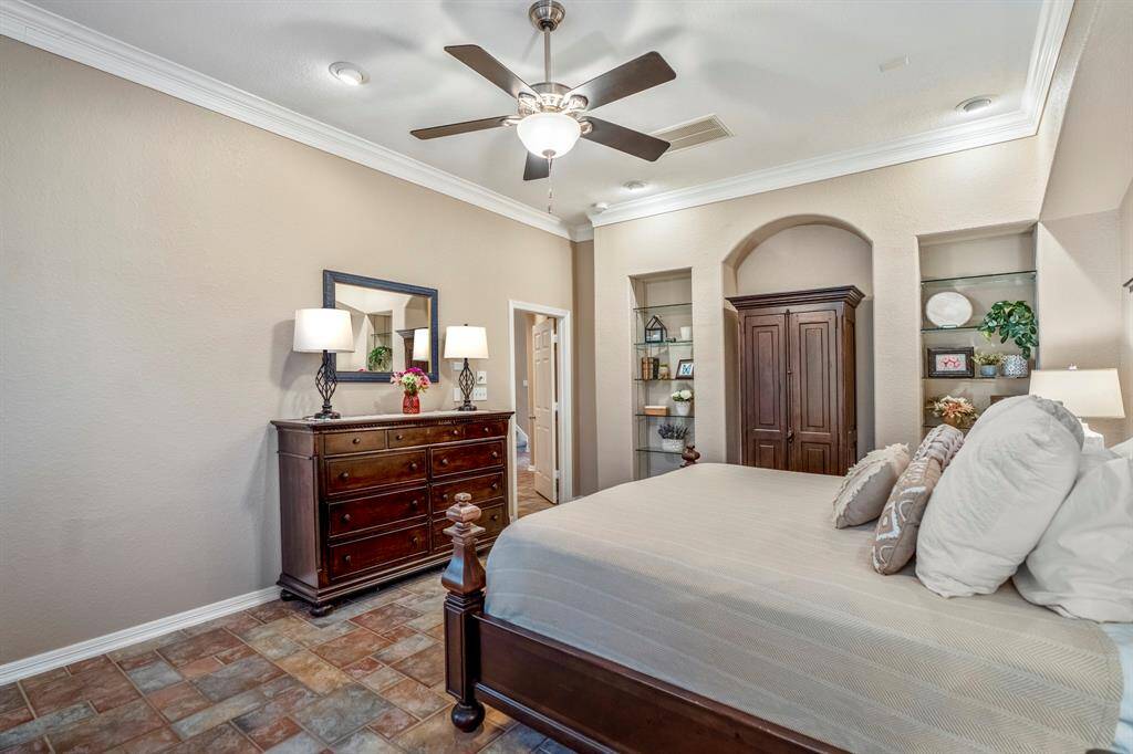 This view of the primary bedroom highlights the elegant recessed arches and built-in glass shelving, illuminated by overhead lighting. These thoughtful design elements add both character and functionality, creating a stylish yet inviting retreat.