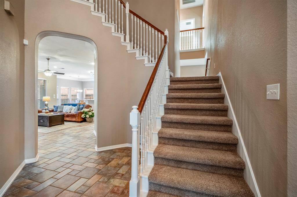 The staircase makes a striking statement with its elegant design and halfway landing, where a second staircase leads down toward the area behind the kitchen. This thoughtful layout adds convenience and connectivity between the home's main and secondary living spaces.