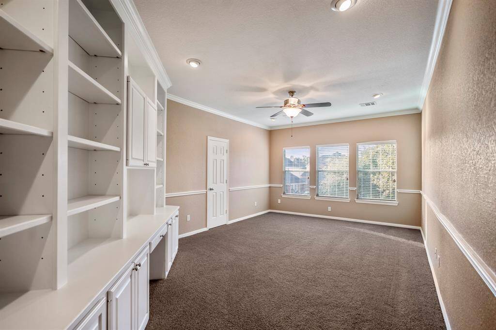 The media room is a flexible space featuring a wall of built-in shelves and cabinets for storage and display. With two large closets, it offers the potential to serve as a sixth bedroom, providing even more versatility to suit your needs.