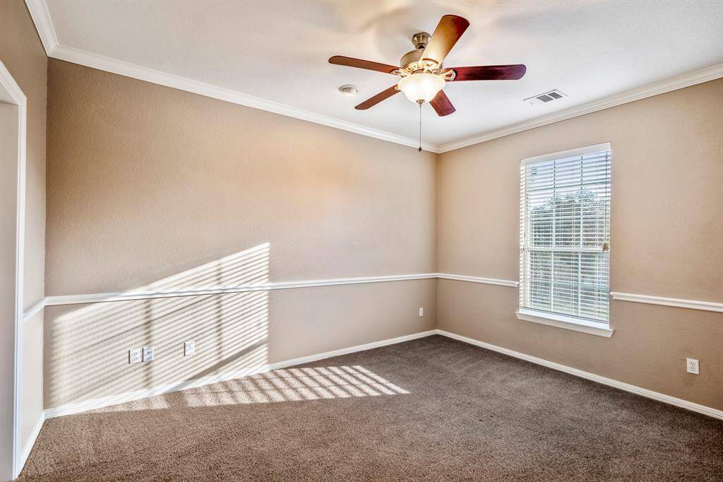 This bedroom, connected by the Jack and Jill bathroom, offers a spacious walk-in closet in its vanity area, providing ample storage. The room is accented with chair railing and crown moulding, adding a touch of elegance. A large window overlooks the front of the home, bringing in natural light and a lovely view.