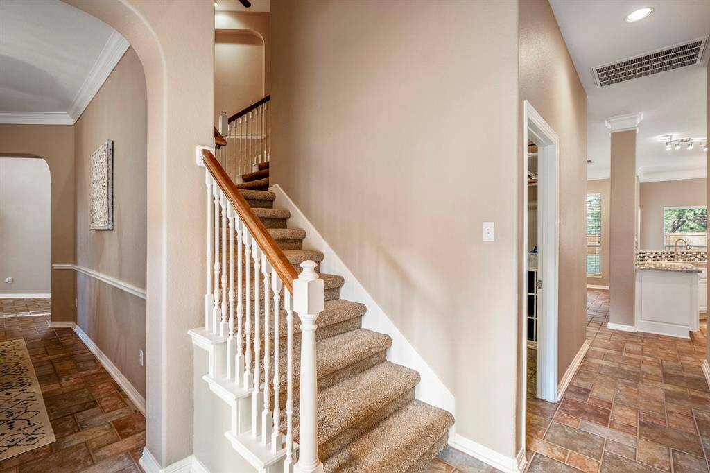 As you descend the back staircase, this vantage point offers a view through the doorway into the formal dining room to the left. Directly behind you, out of view, is the second entrance to the home near the driveway. Straight ahead, the hallway leads to the kitchen, with the laundry room on the left and a full bathroom and the third home office/study on the right.