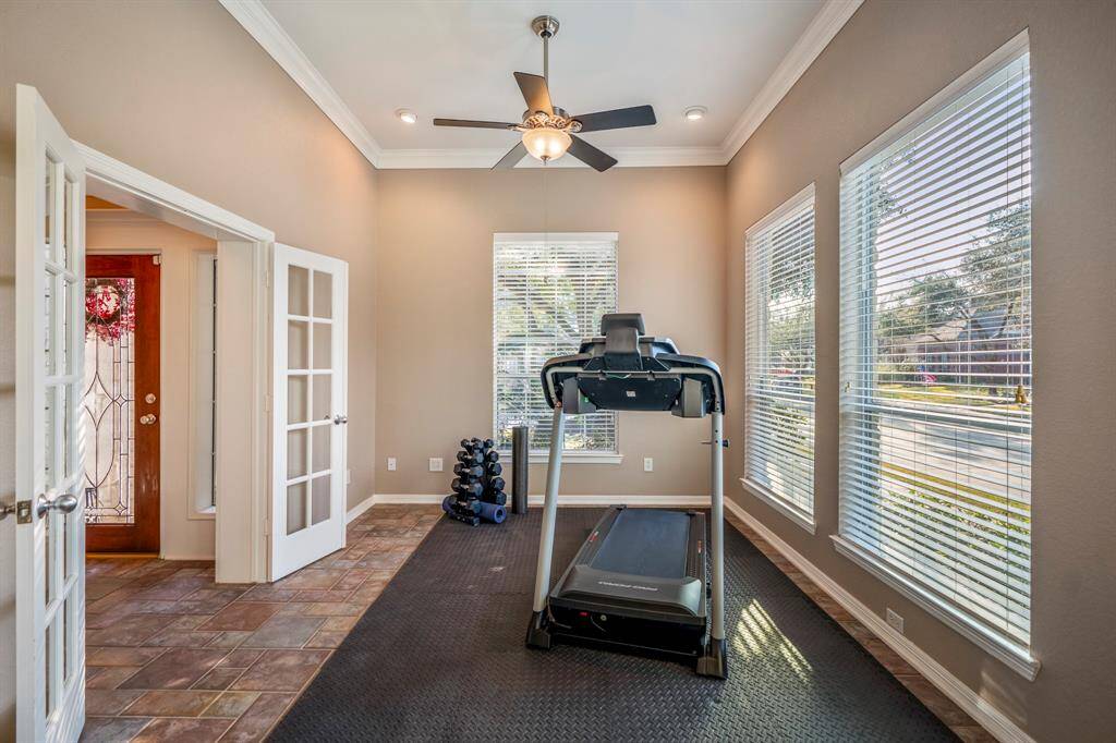 This bright and versatile space, currently used as a home gym, features large windows overlooking the front and side yard, bringing in plenty of natural light. Crown molding and tile flooring add a touch of elegance, making it perfect for a formal living room, office, or workout area.