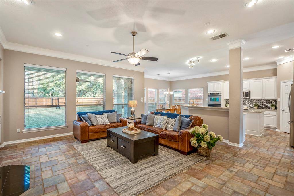 Entering the family room, you'll immediately notice the open, airy feel, with large windows along the rear of the home bringing in an abundance of natural light. The space flows seamlessly into the kitchen and breakfast area, creating the perfect spot for gatherings. Tile flooring and double crown molding throughout add a refined touch to the expansive room.