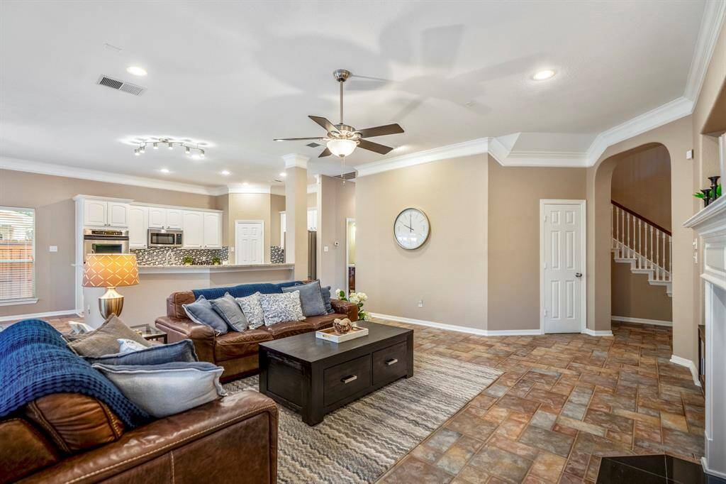 From this corner view of the family room, the cozy fireplace adds warmth to the space, while large windows continue to bathe the room in natural light. A convenient storage closet sits near the doorway leading back to the foyer, with a glimpse of the stairs just beyond. To the left, the hallway behind the kitchen offers easy access to the laundry room, a full bathroom, the second study/home office, and a back staircase. The second entrance near the driveway adds extra convenience.