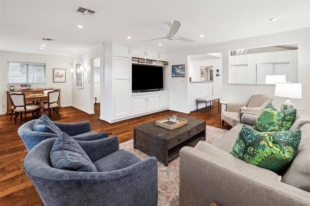 Relax and unwind in this welcoming living room surrounded by a wall of built-in cabinetry, painted brick and a new ceiling fan.
