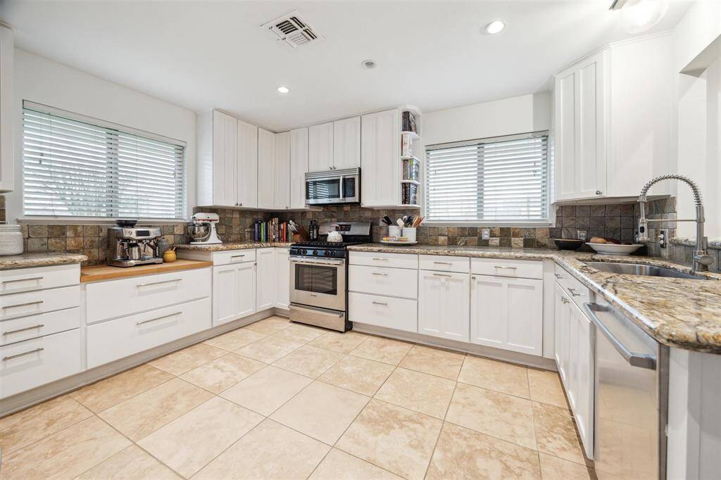 Recessed LEDs, a pendant fixture, under-cabinet lighting and two big windows add tons of light to this charming kitchen.