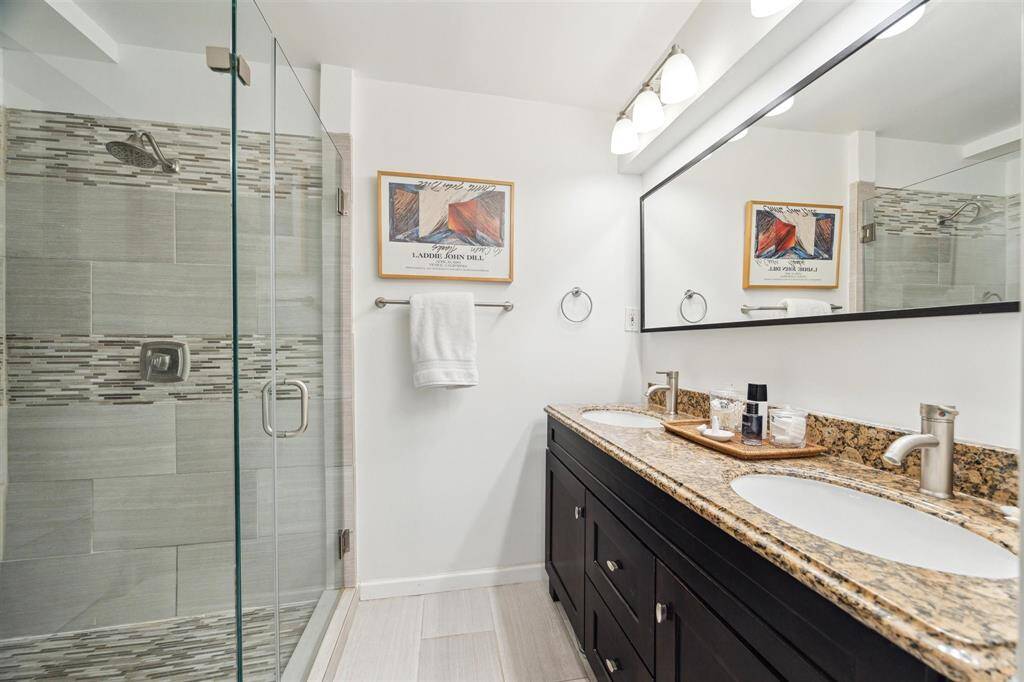 The en suite bathroom impresses with a frameless glass rain shower and a wide double vanity with generous storage.