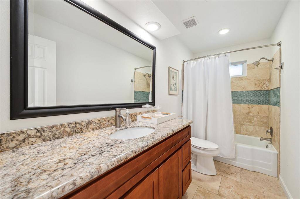 In the windowed guest bathroom, you’ll find a wide granite vanity and a large tub/shower all surrounded by travertine tile.