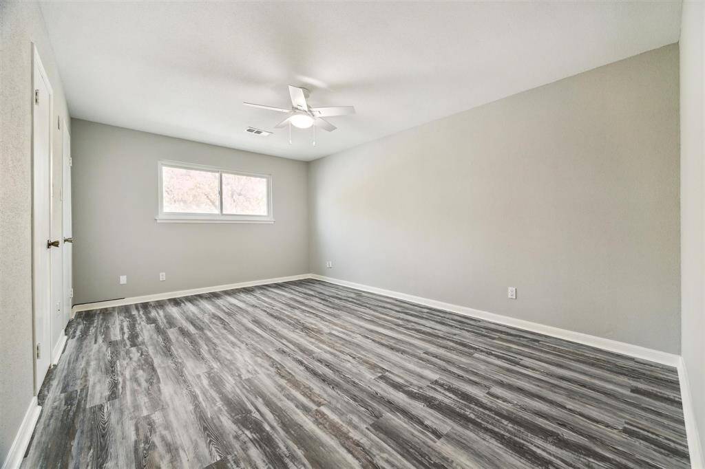 The spacious primary bedroom boasts beautiful flooring, a ceiling fan with light, and a generous walk-in closet.