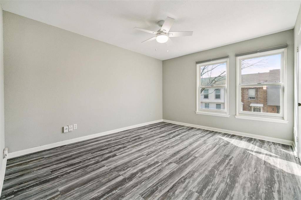 This secondary bedroom showcases stunning flooring, a ceiling fan with light, a spacious walk-in closet and fantastic windows that fill the room in natural light. .