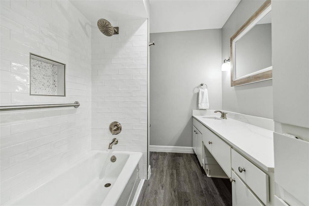 The secondary bathroom features a sleek tub/shower combination with elegant subway tile, complemented by a quartz countertop with vanity space.