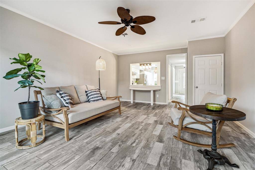 The spacious living room boasts crown molding, a ceiling fan, and an opening to the kitchen, designed for easy conversation flow.