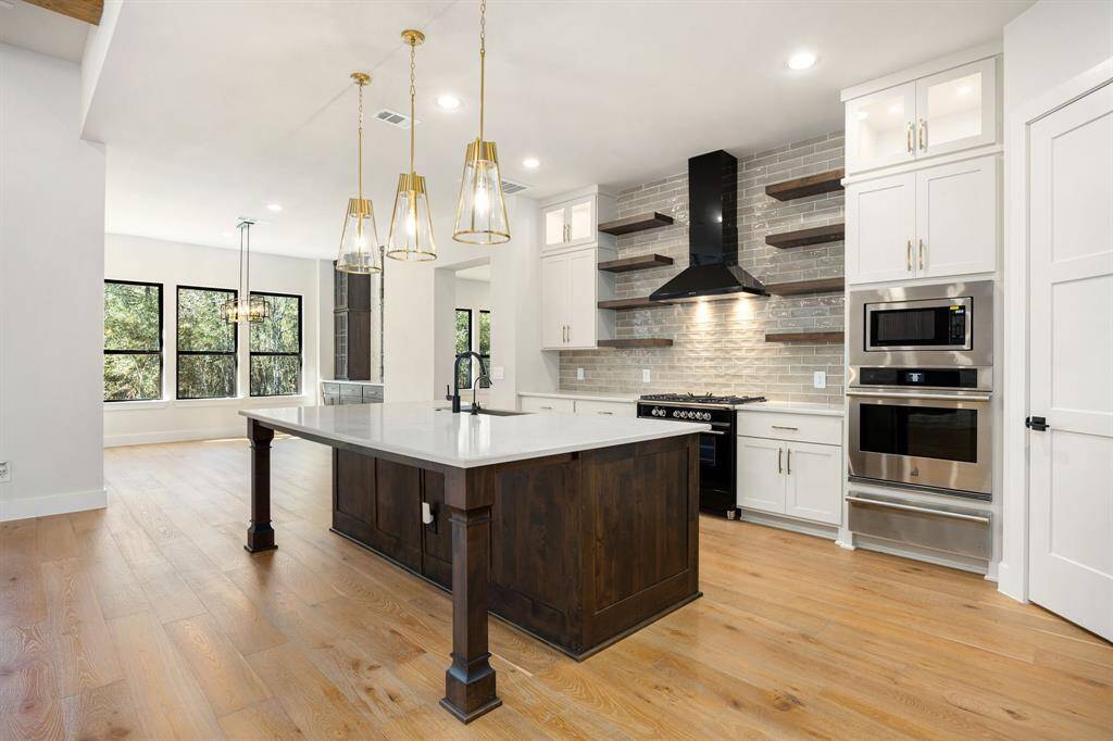 Open island Kitchen with stainless steel appliances and floating shelves