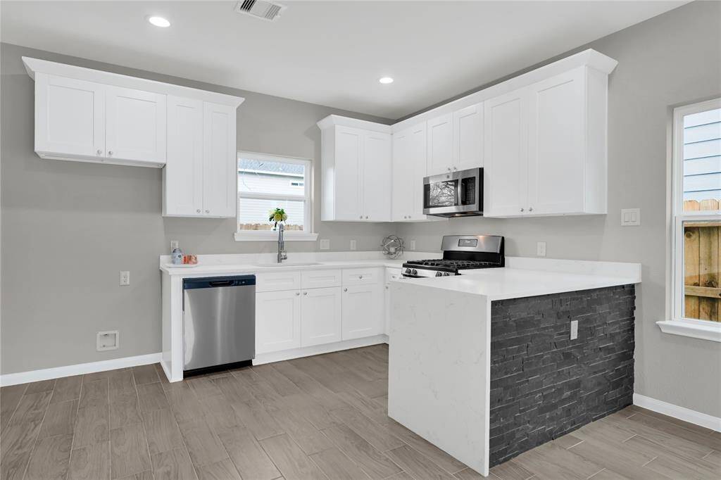 Modern and inviting kitchen featuring sleek white cabinetry, stainless steel appliances, and a chic stone-accented island. Perfect for culinary enthusiasts!