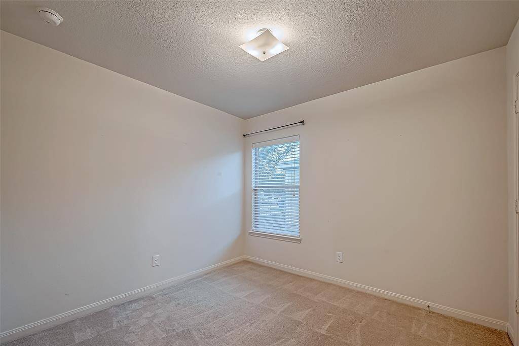 This photo shows a neutral-toned secondary bedroom 2 with a carpeted floor and a single window allowing natural liight.