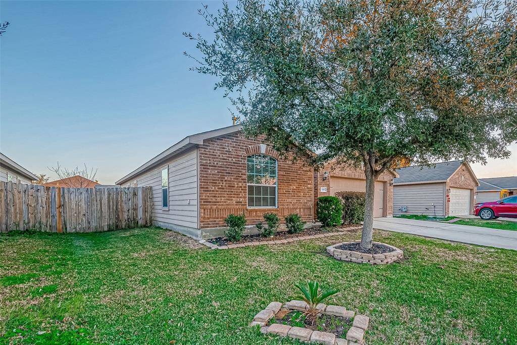 Charming single-story home with a brick facade, featuring a well-maintained front yard and mature tree. The property includes a wooden fenced backyard and a concrete driveway leading to an attached garage. Ideal for buyers looking for a cozy and inviting neighborhood setting.