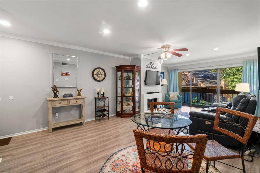 This inviting living space features a cozy seating area with a ceiling fan, modern laminate flooring, and a large glass sliding door leading to a deck. Ample natural light, creating a bright and welcoming atmosphere.
