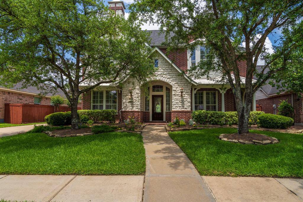 Charming brick and stone home with inviting curb appeal. Nestled among mature trees, this residence features a beautifully manicured lawn and a welcoming arched entryway. Perfect for comfortable living in a serene neighborhood.