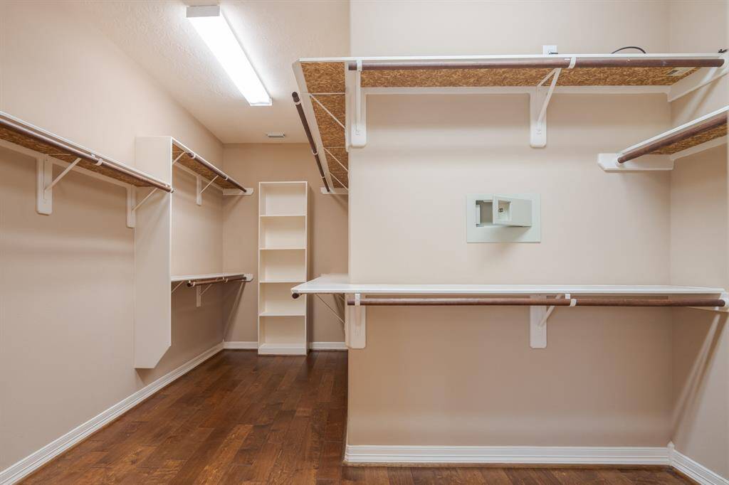 Spacious walk-in closet with ample shelving and hanging space, perfect for organizing your wardrobe. Elegant wood flooring adds a touch of luxury.