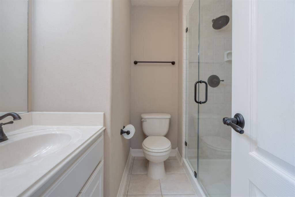 Modern bathroom featuring a sleek glass shower, elegant fixtures, and a convenient vanity. Ideal for a stylish, functional space.
