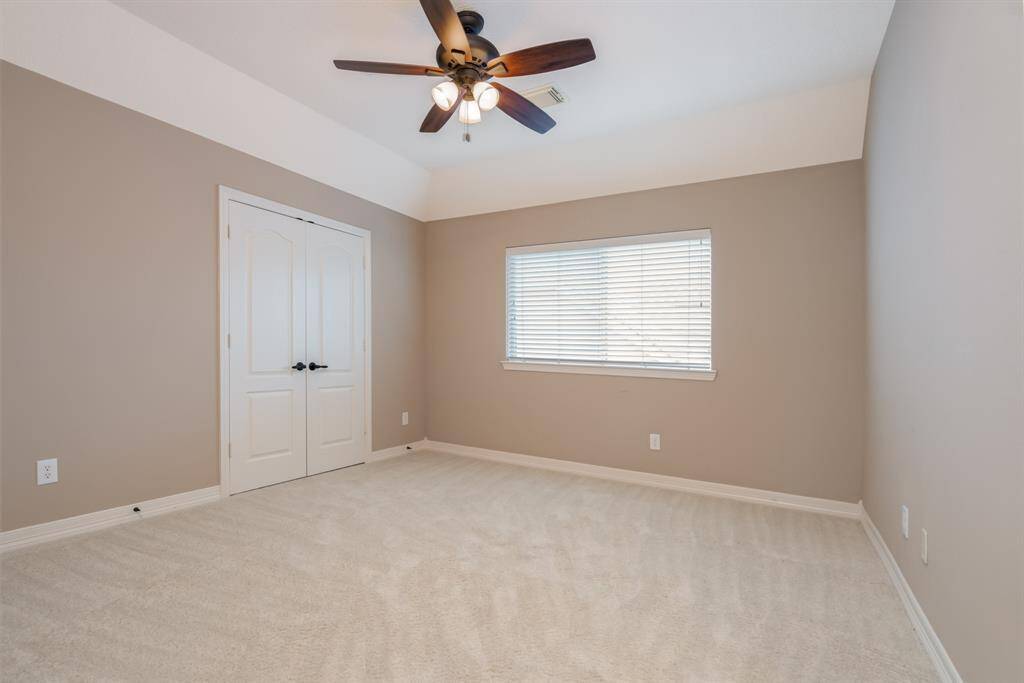 Discover a bright, spacious bedroom featuring neutral tones, plush carpeting, and a ceiling fan for comfort. The large window invites natural light, and double doors offer ample closet space, creating a perfect retreat.