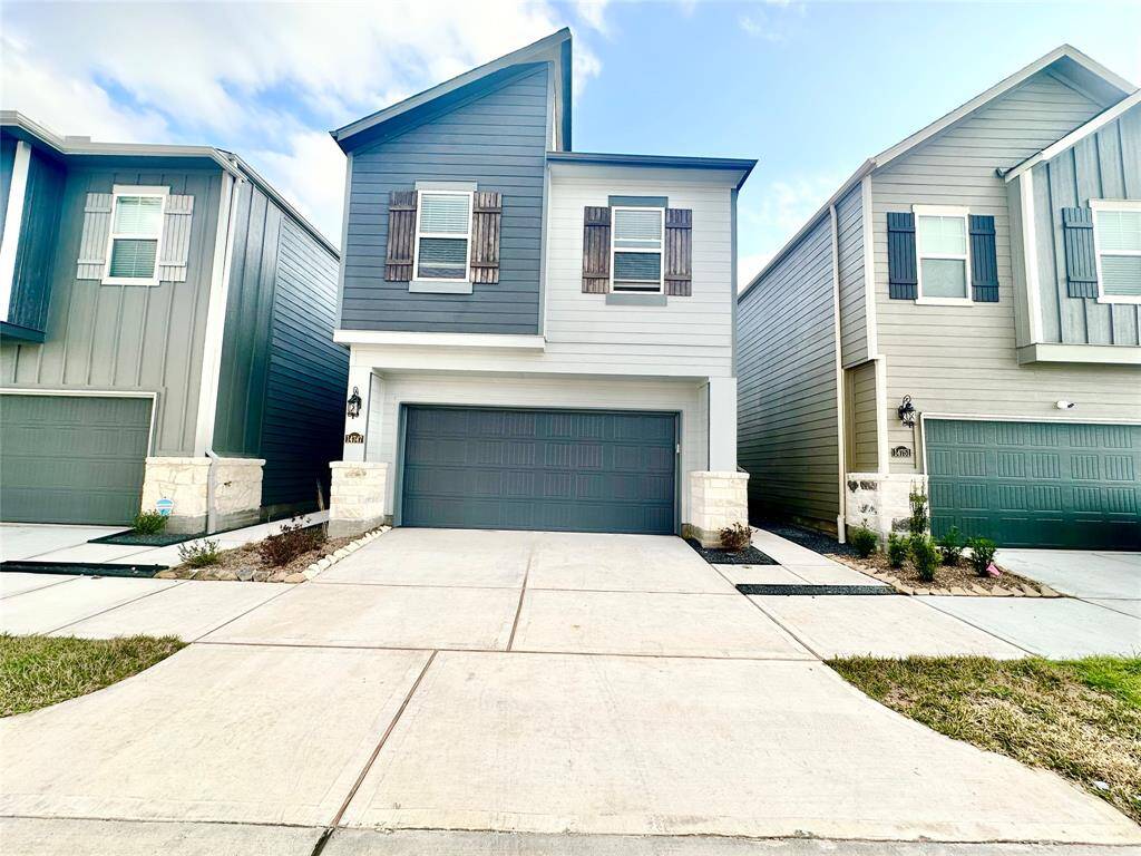 Modern two-story townhome with a gray exterior, featuring a double garage and a clean, minimalist front yard. Located in a row of similar style houses, it offers a contemporary and cohesive neighborhood feel.