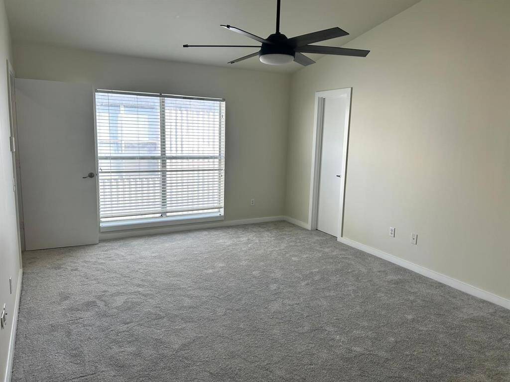 Light and bright bedroom with ceiling fan and new carpet.